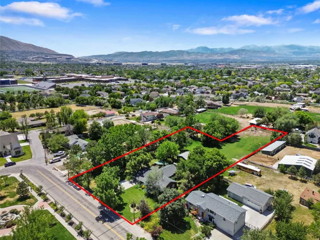 Expansive property outlined in red, featuring a substantial land area with mature trees and open green spaces
