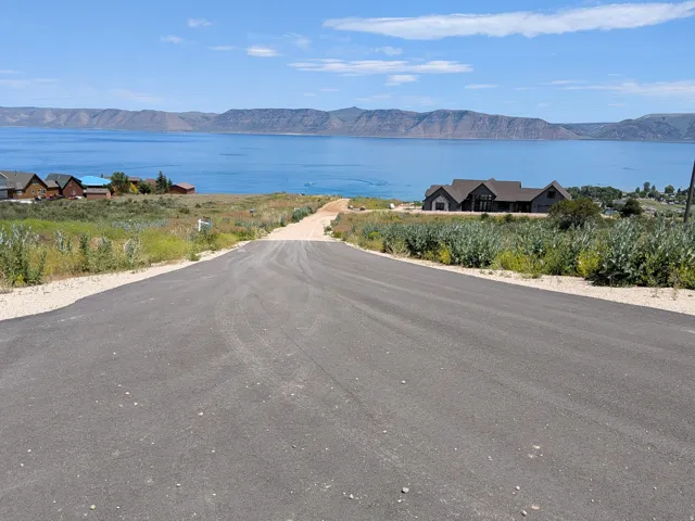 Paved road leading towards a large body of water with distant mountains