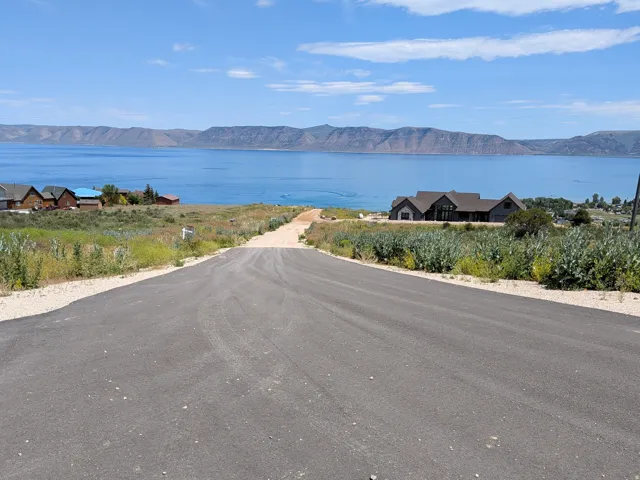 Paved road leading towards a large body of water with distant mountains