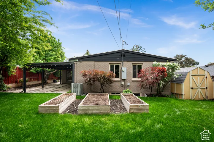 Expansive backyard featuring a manicured lawn, three raised garden beds, and a detached storage shed