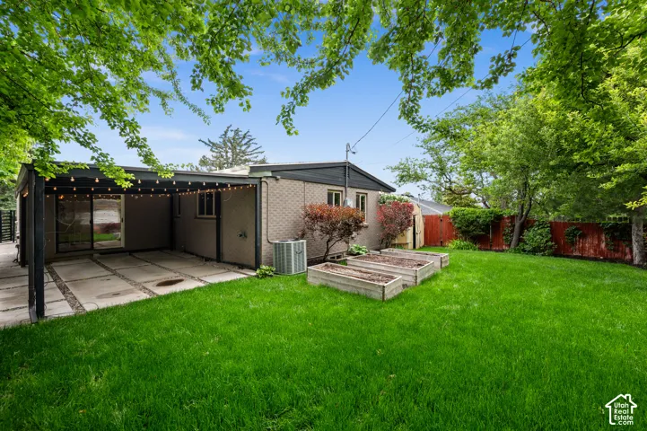 Expansive backyard featuring a manicured lawn, mature trees, and raised garden beds