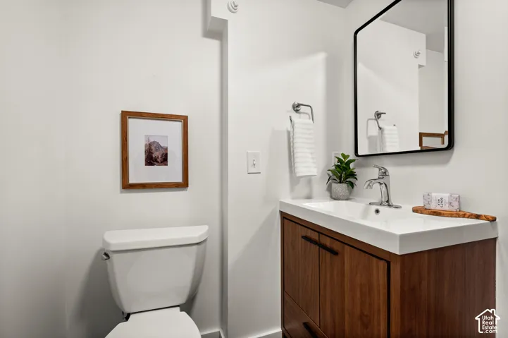 Modern vanity featuring a wood-finish cabinet with black hardware, a rectangular integrated sink, and a chrome faucet