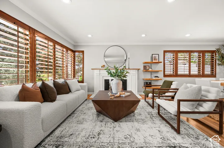 Bright living area featuring a white mantel fireplace, recessed lighting, and wood-finish flooring