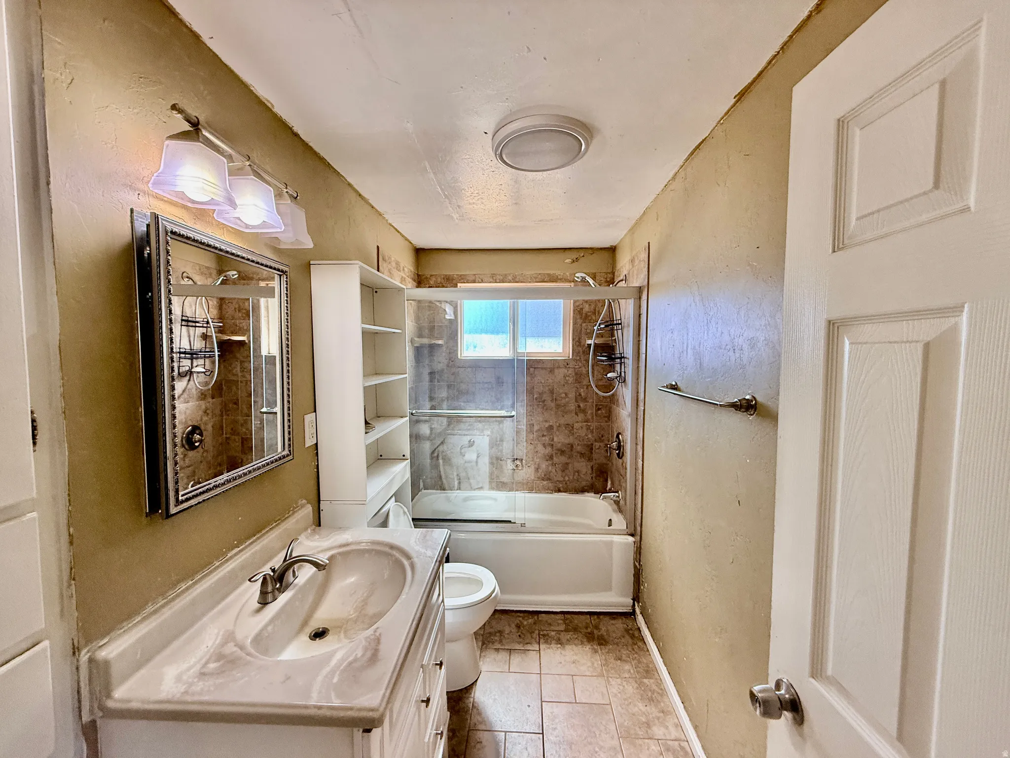 Bathroom featuring a combination tub/shower with tiled surround and glass enclosure