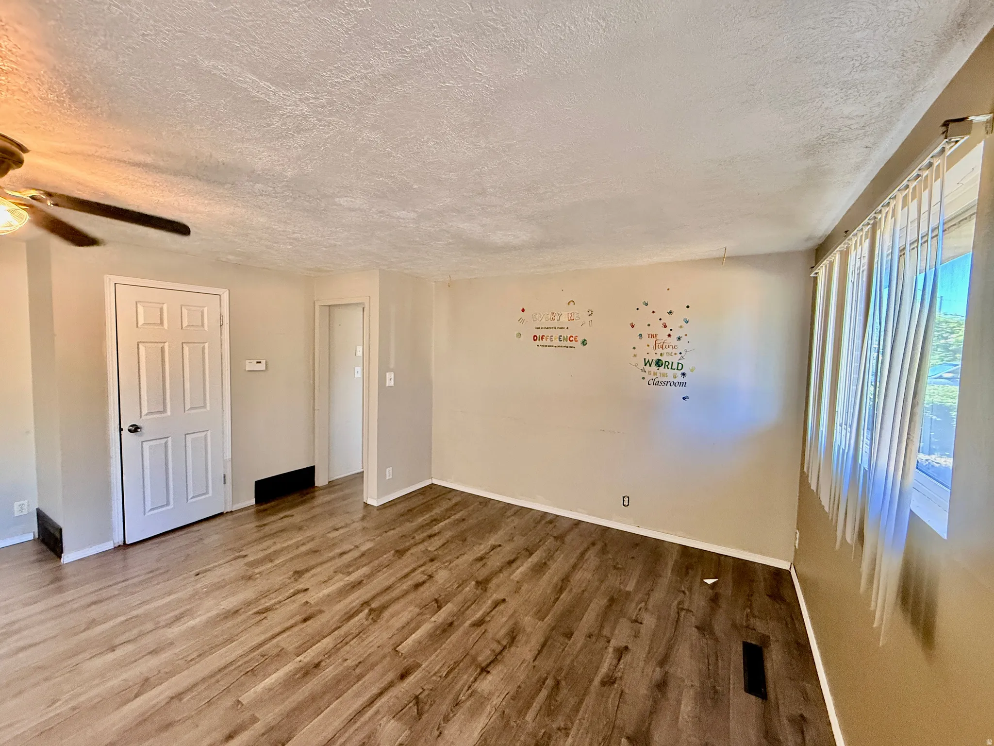 Spacious room featuring wood-finish flooring, light-toned walls, and a multi-pane window