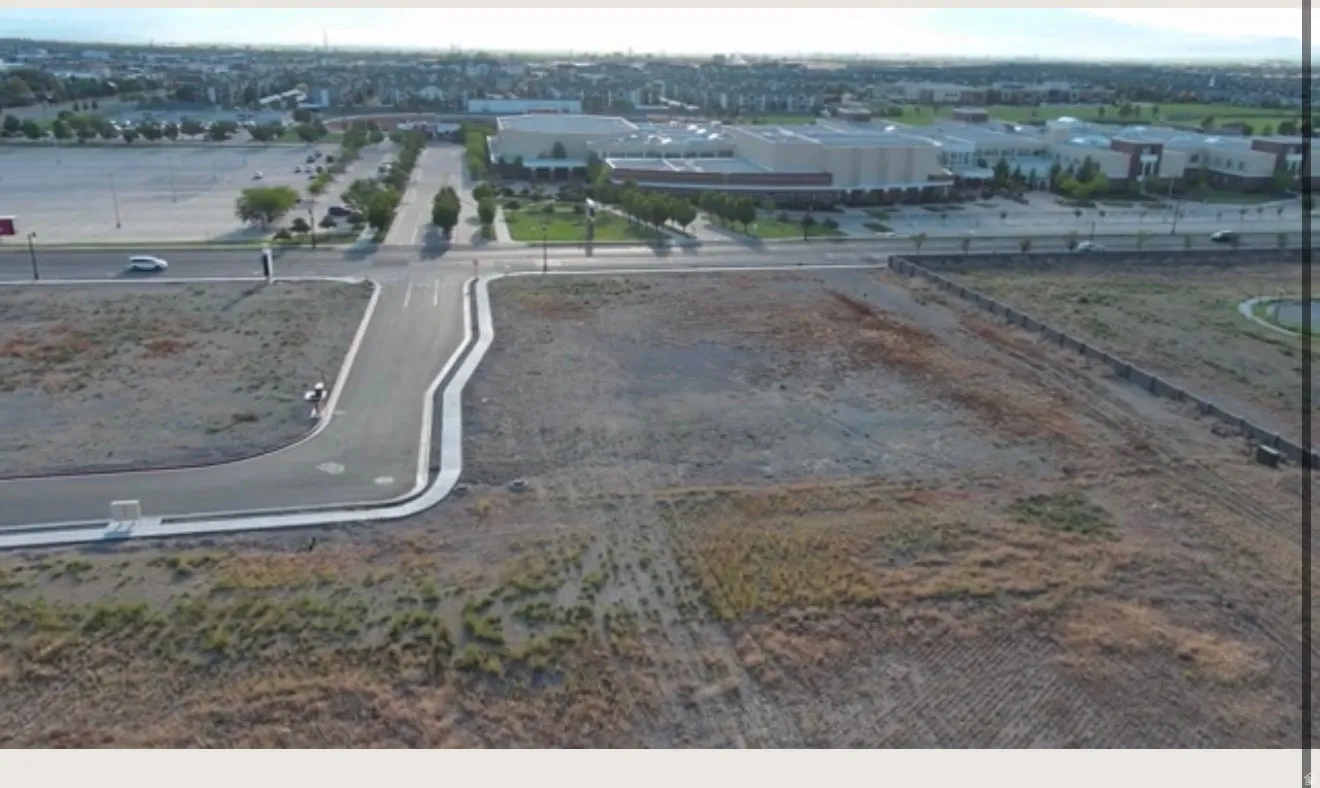 Expansive, undeveloped parcel with a newly paved street and concrete curbing