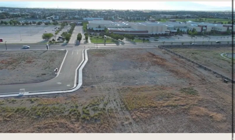 Expansive, undeveloped parcel with a newly paved street and concrete curbing