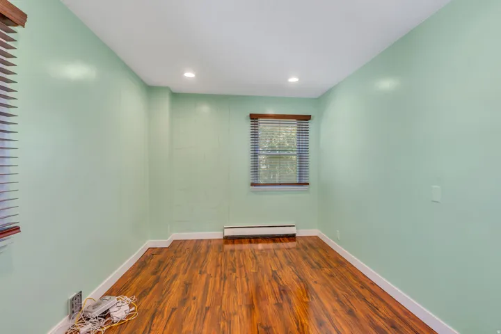 Room featuring wood-finish flooring, two windows with wooden blinds, recessed ceiling lighting, and light green walls