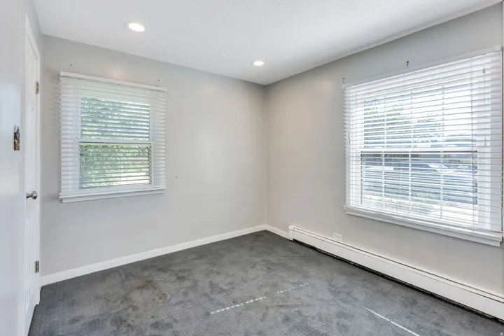 Room featuring light gray walls, two windows with white blinds, and recessed ceiling lighting