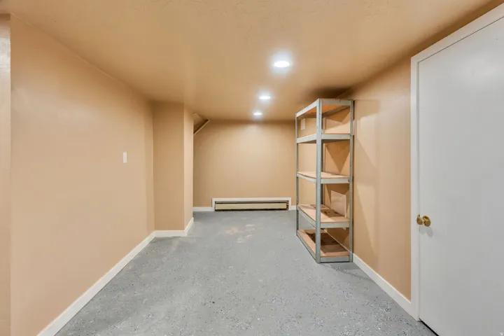 Finished basement area featuring recessed lighting, a utility door, and durable concrete flooring