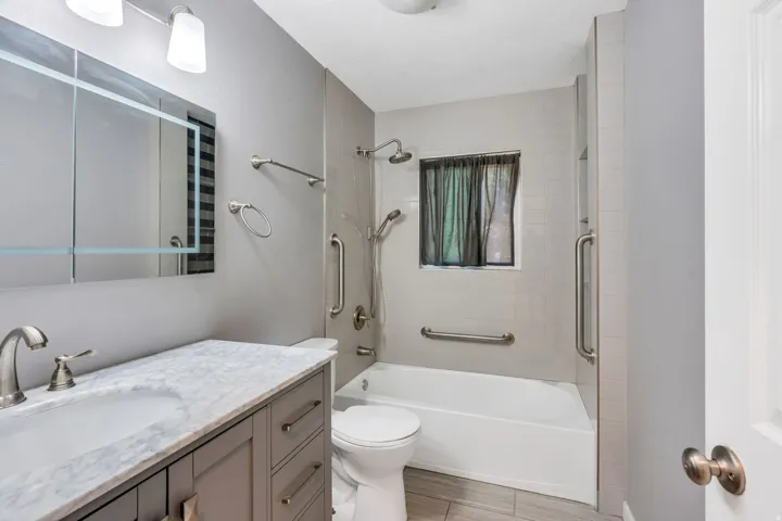 Bathroom featuring a gray vanity with a stone countertop, an integrated sink, and brushed nickel hardware