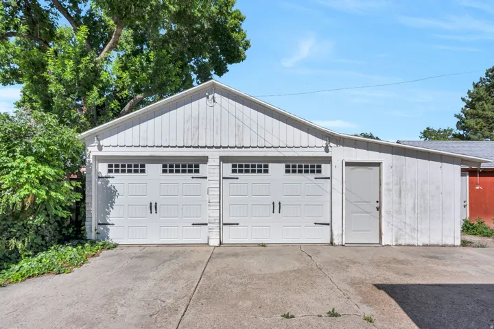 Detached two-car garage with white paneled doors featuring decorative hardware