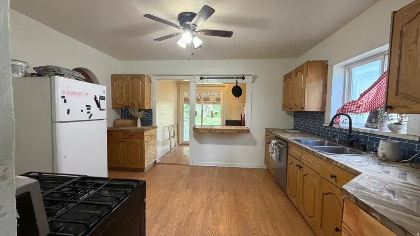 Kitchen featuring wood-finish flooring, natural wood cabinetry, and an undermount double-basin sink
