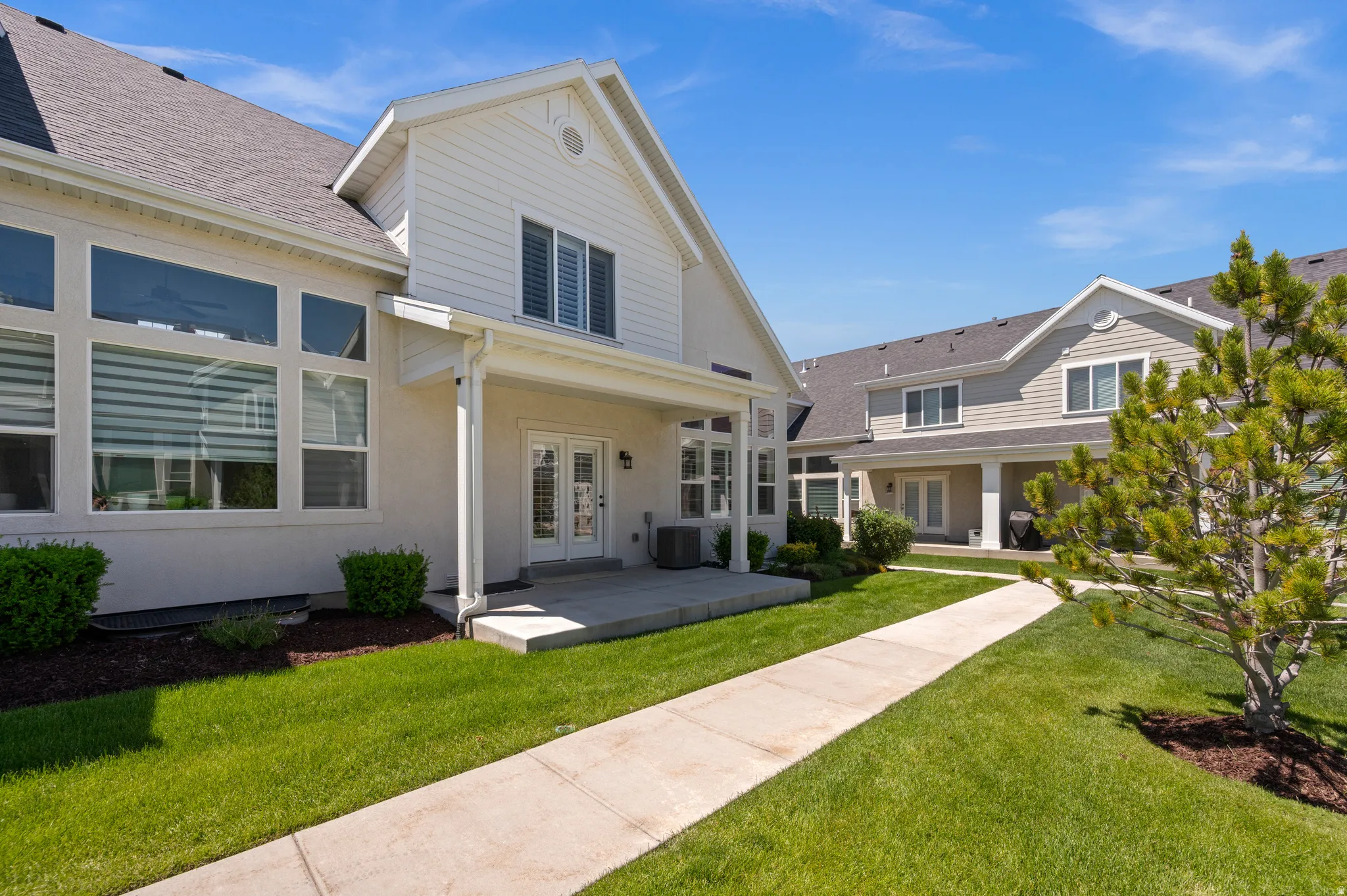 White siding exterior with a dark shingle roof and a covered patio
