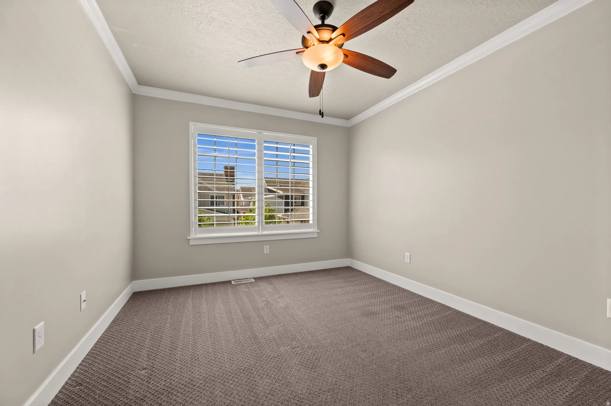 Bedroom featuring a ceiling fan with integrated lighting, crown molding, and neutral-toned carpeting