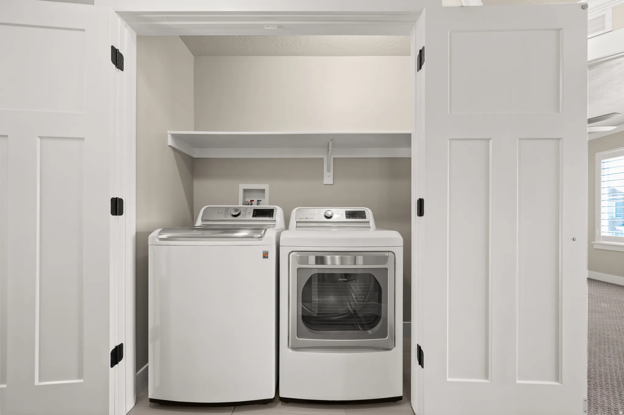 Utility closet featuring a built-in shelf, neutral wall tones, and panel doors with dark hardware