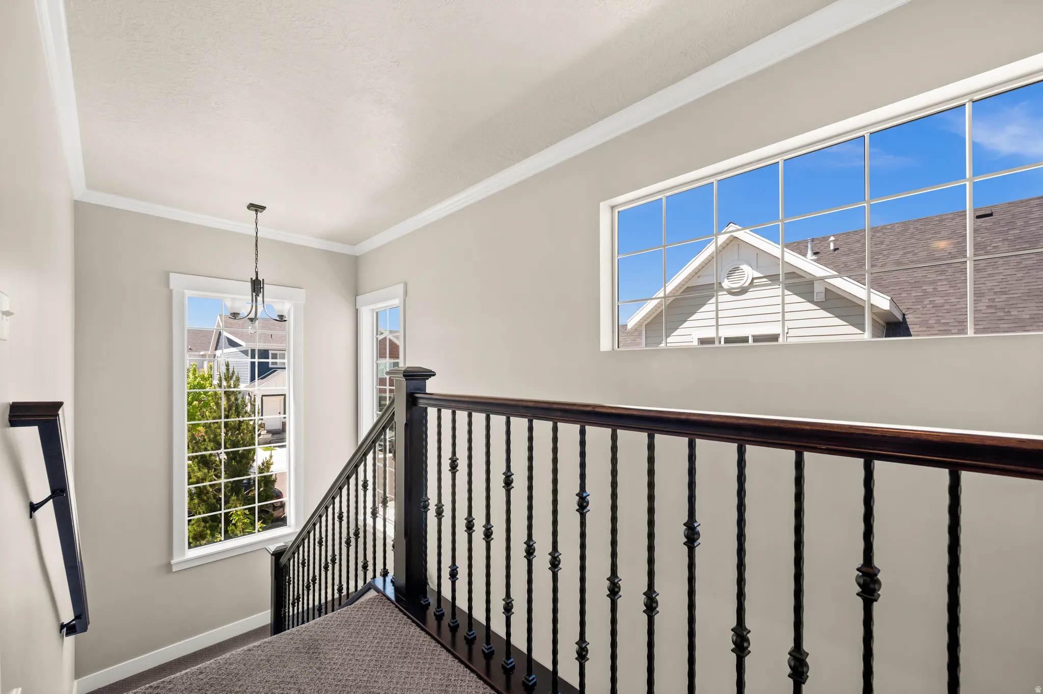 Upper landing featuring a wrought iron banister with wood-finish railing