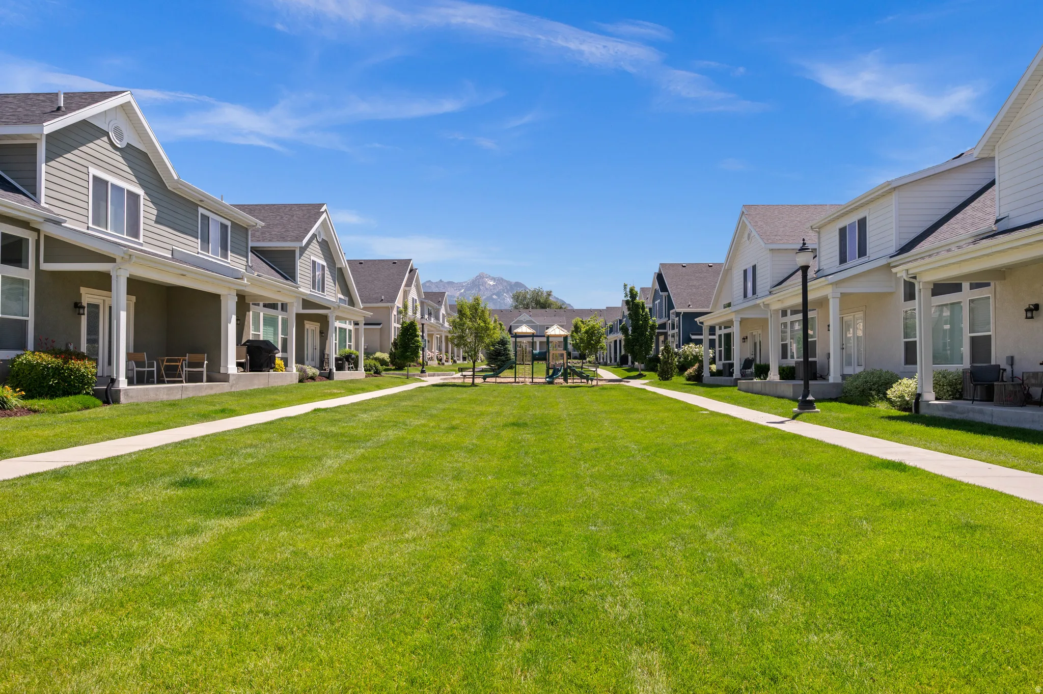 Expansive central green space featuring a playground and mountain backdrop
