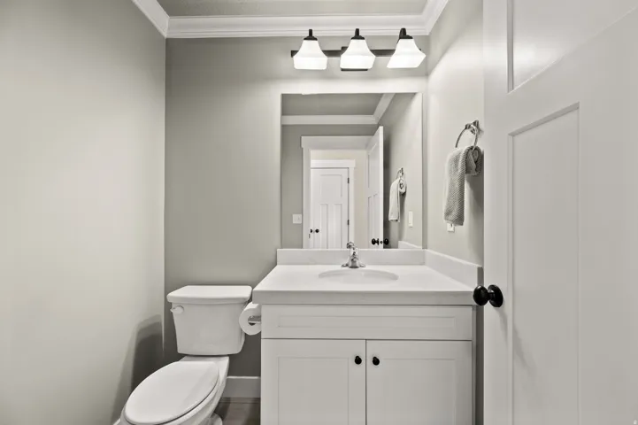 Bathroom featuring a white vanity with a white countertop, an undermount sink, a chrome faucet, and a large mirror