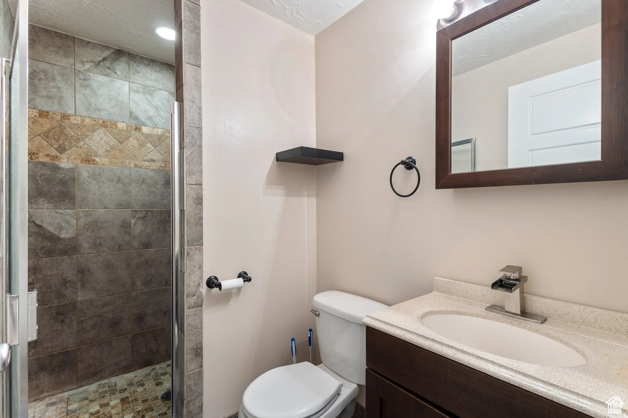 Walk-in shower with stone tile surround and decorative accent band
