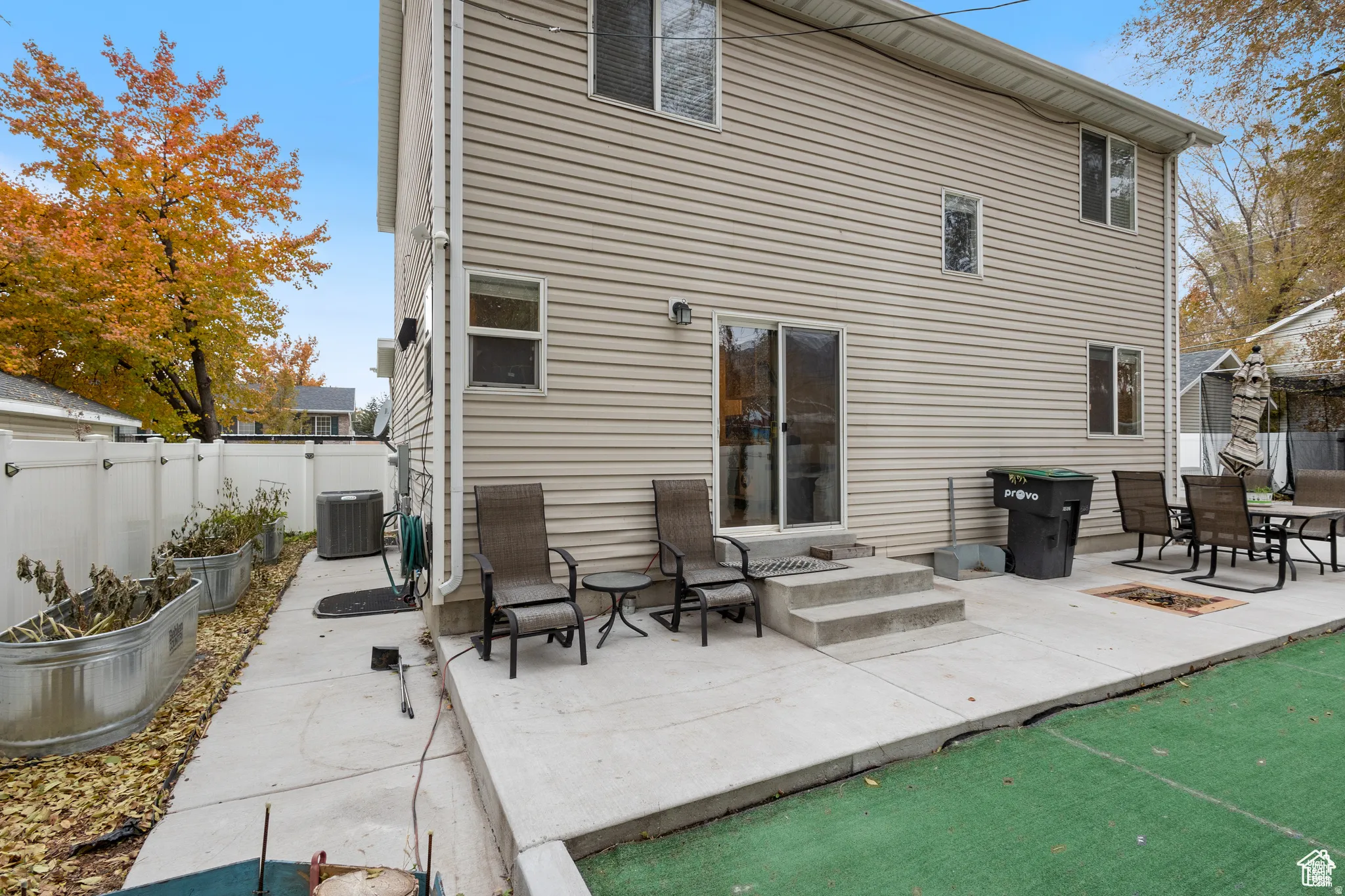 Rear exterior featuring beige siding, multiple windows, and a sliding glass door