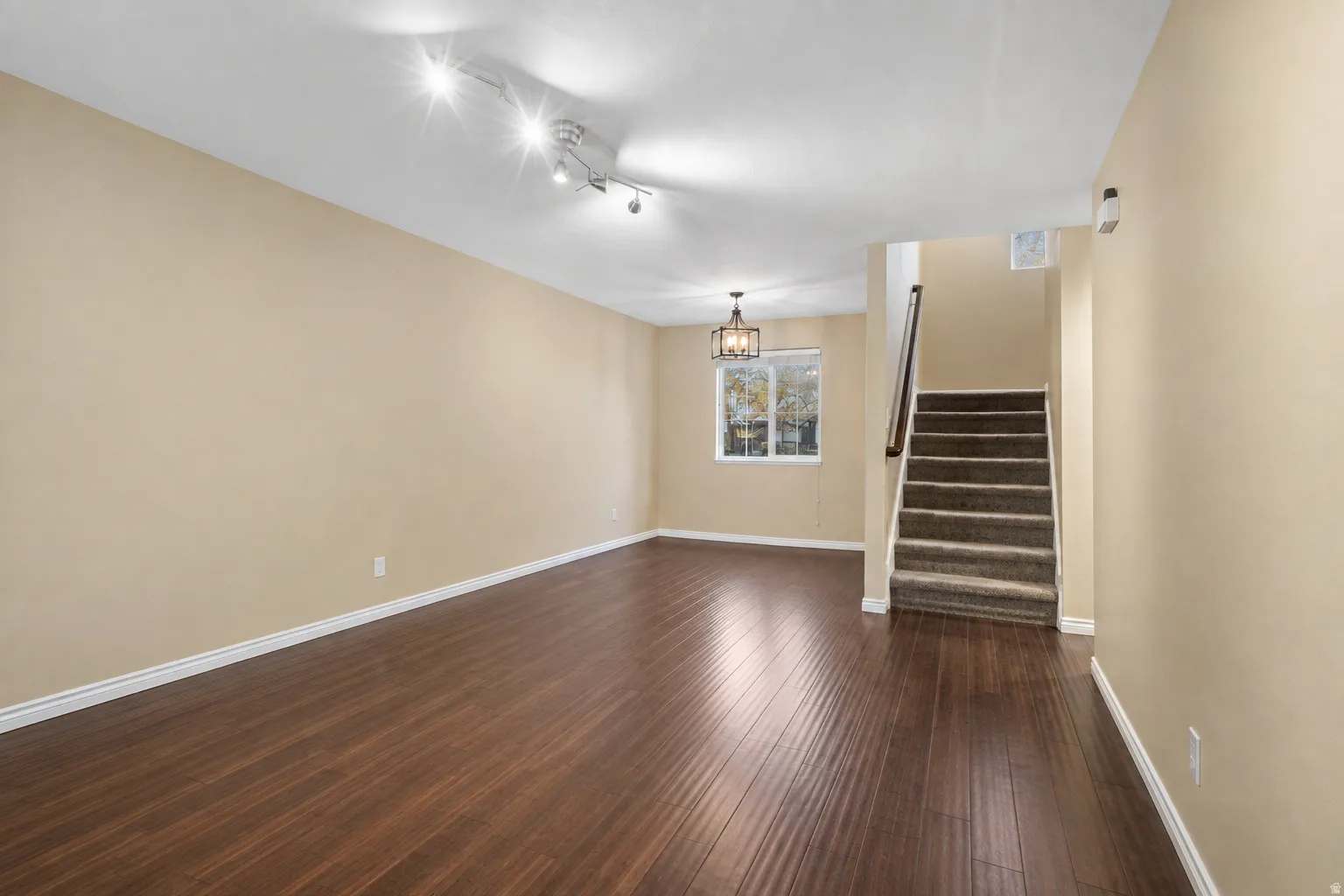 Wood-finish flooring, recessed lighting, track lighting, traditional chandelier, and carpeted stairs