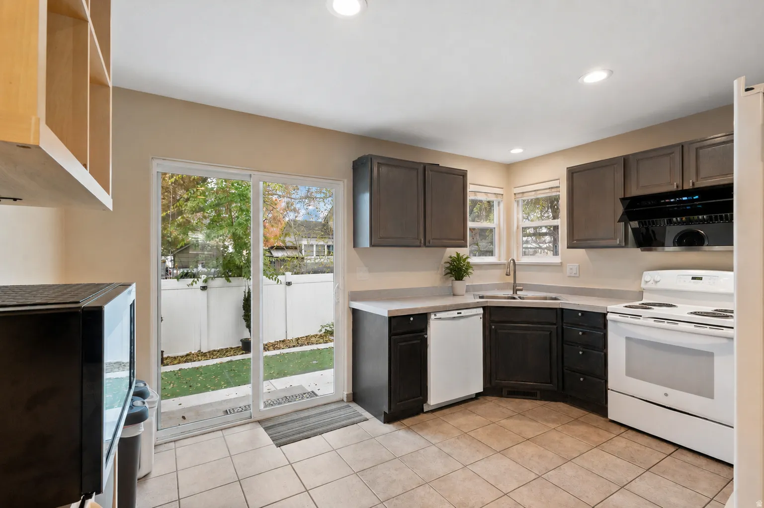 Kitchen featuring dark wood-finish cabinetry, light-toned countertops, tile flooring, and a glass sliding door