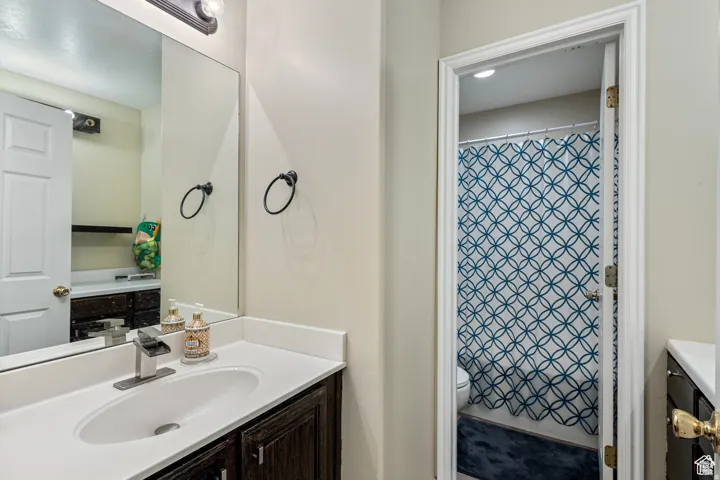 Bathroom featuring a single vanity with a white countertop, an undermount sink, and dark wood-finish cabinetry