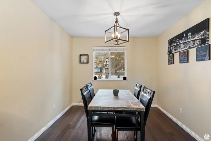 Dining area featuring dark wood-finish flooring, neutral-toned walls, and white baseboards