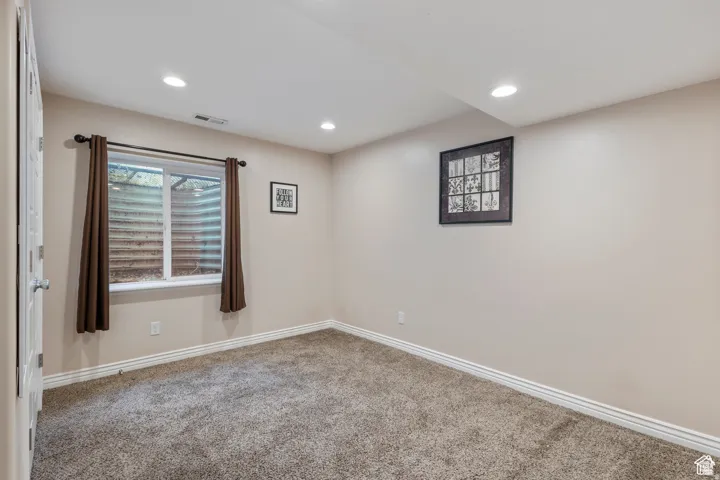 Carpeted room featuring a window with a window well, recessed lighting, and neutral wall paint