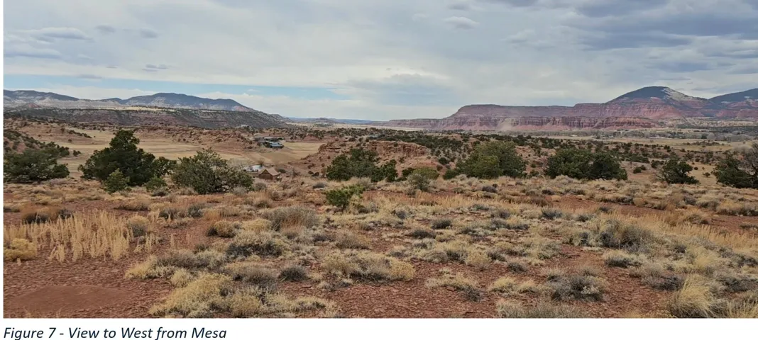 Expansive desert landscape featuring natural brush, varied terrain, and distant mountains