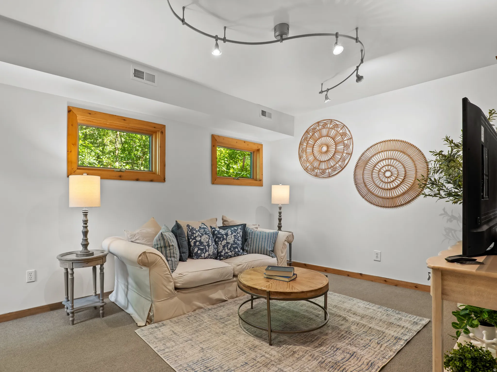 Carpeted floor room featuring two wood-framed windows,and  track lighting