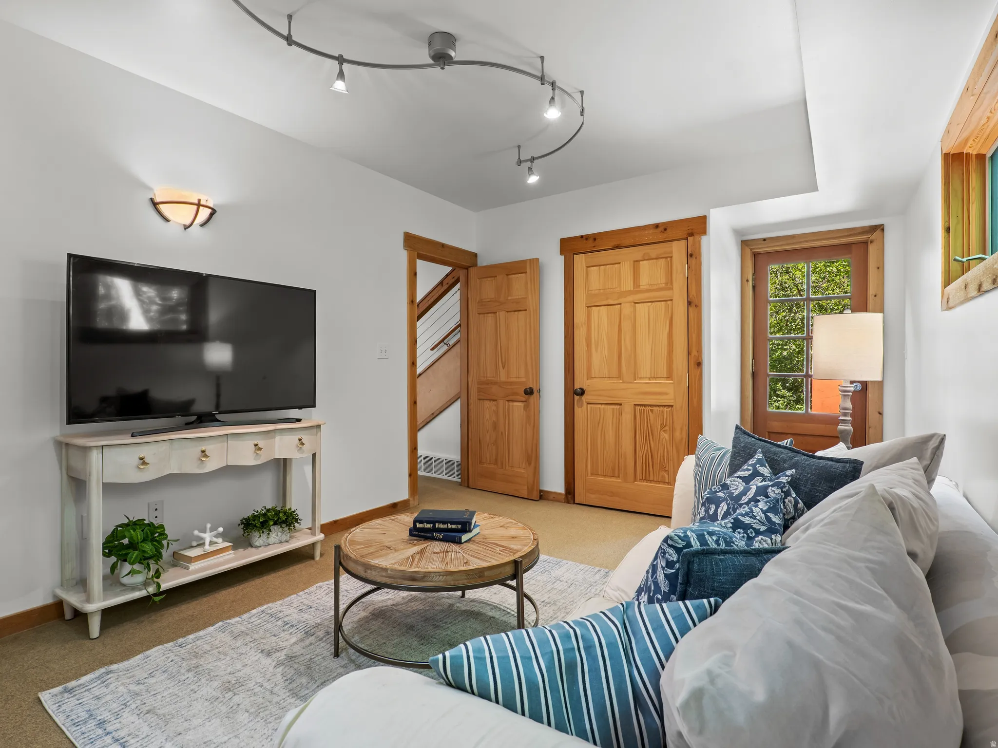 Living area with wood-finish doors and trim, track lighting, and wall sconce