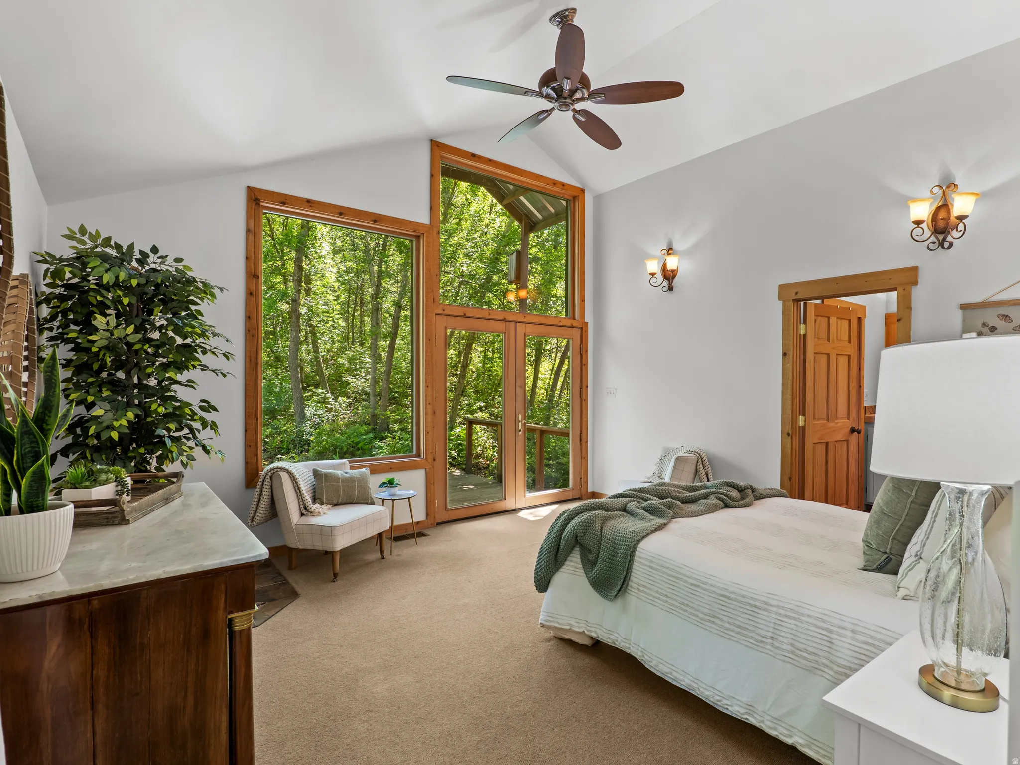 Vaulted ceiling featuring a ceiling fan, full-height windows, a glass door, and sconce lighting