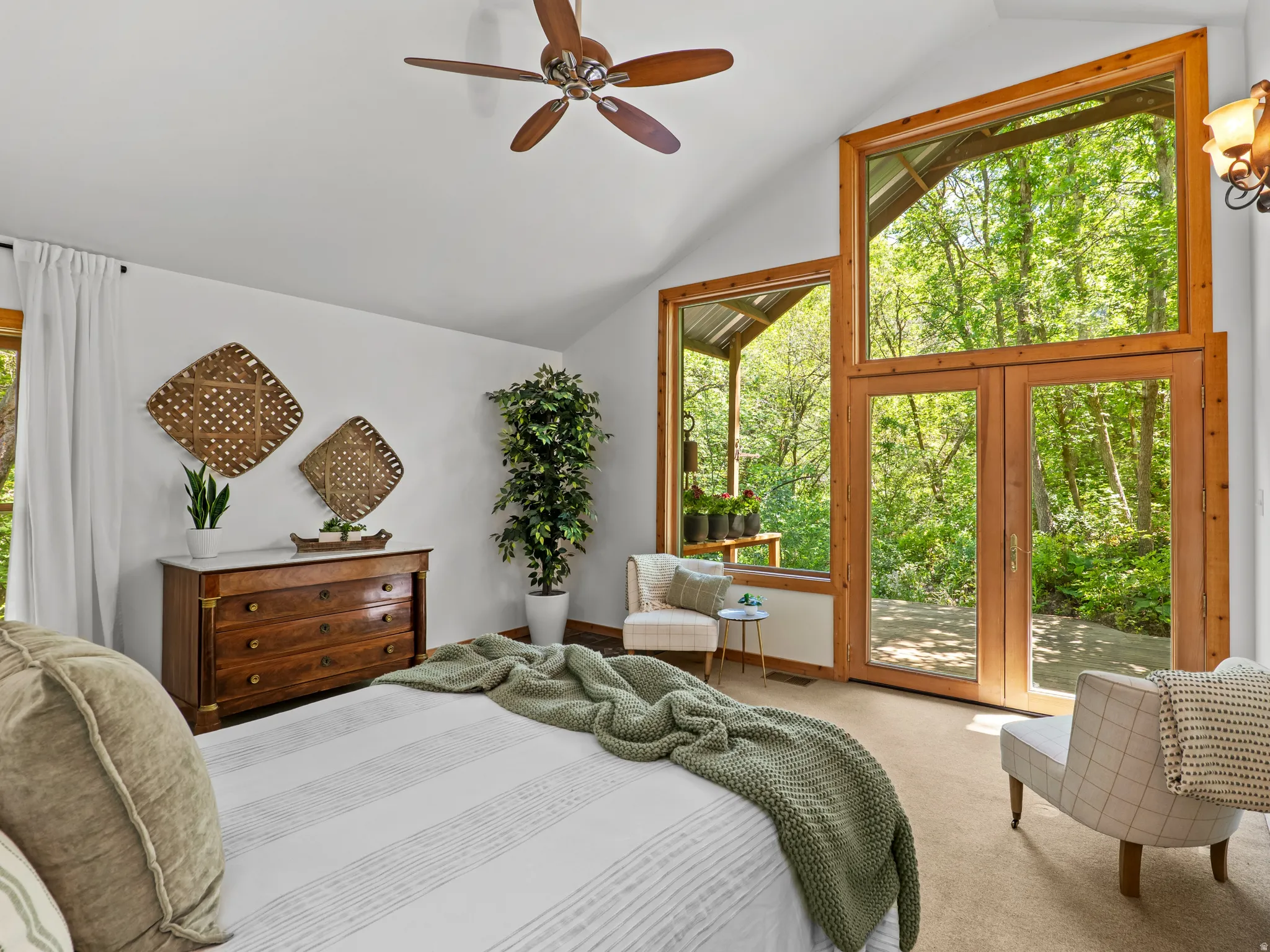Vaulted ceilings with a ceiling fan, a large wooden framed window, a pair of wooden framed doors, and light-colored carpet flooring