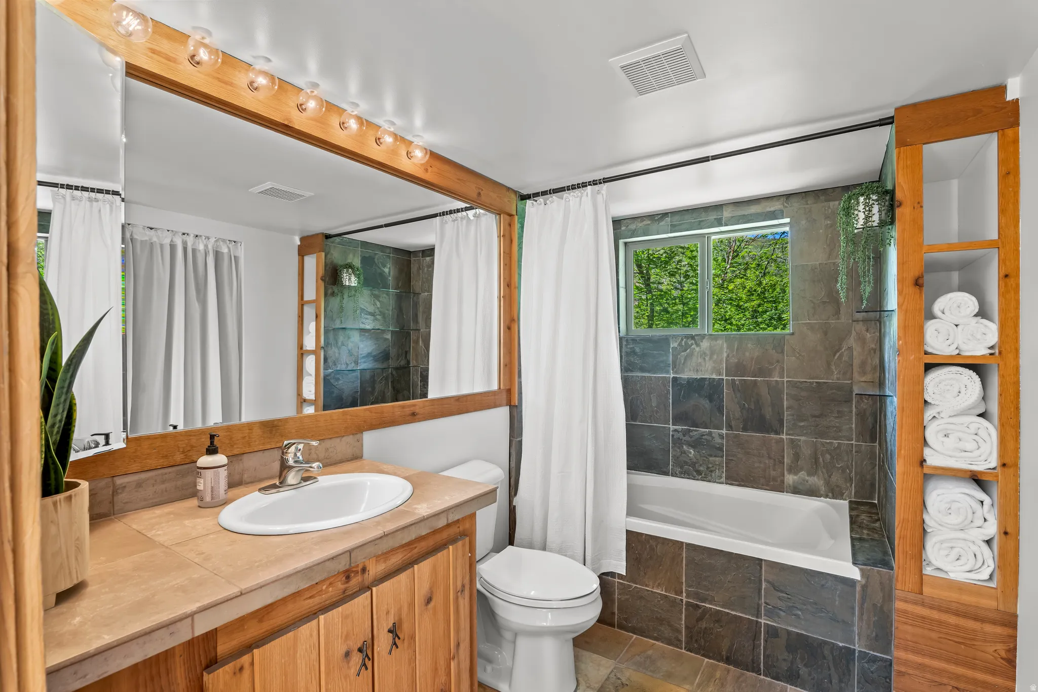 Bathroom featuring a large wood-framed vanity mirror  and deep soaker tub
