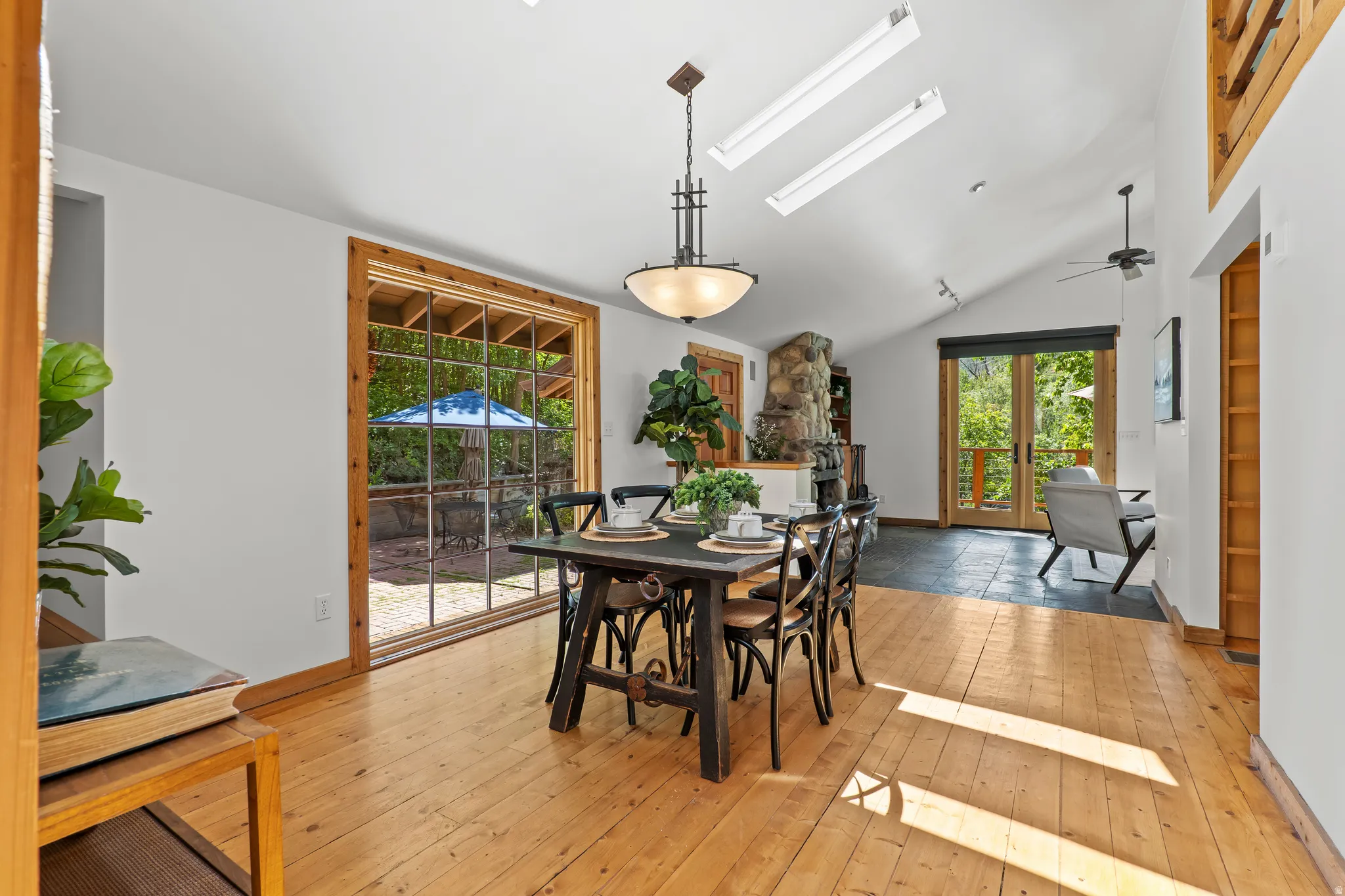 Open dining area with natural wood flooring, a vaulted ceiling and floor to cieling windows