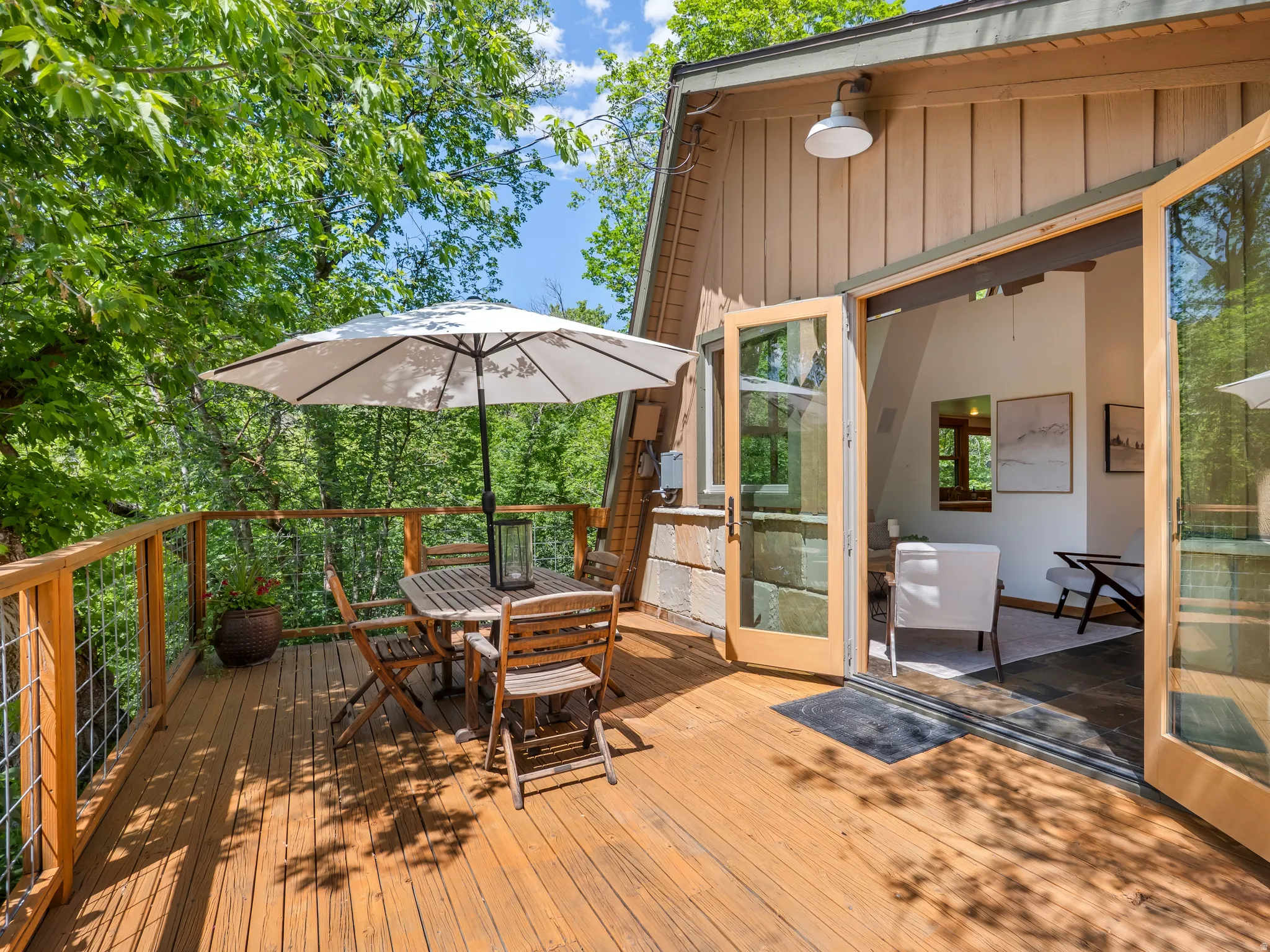 Spacious wood deck with railing surrounded by mature trees
