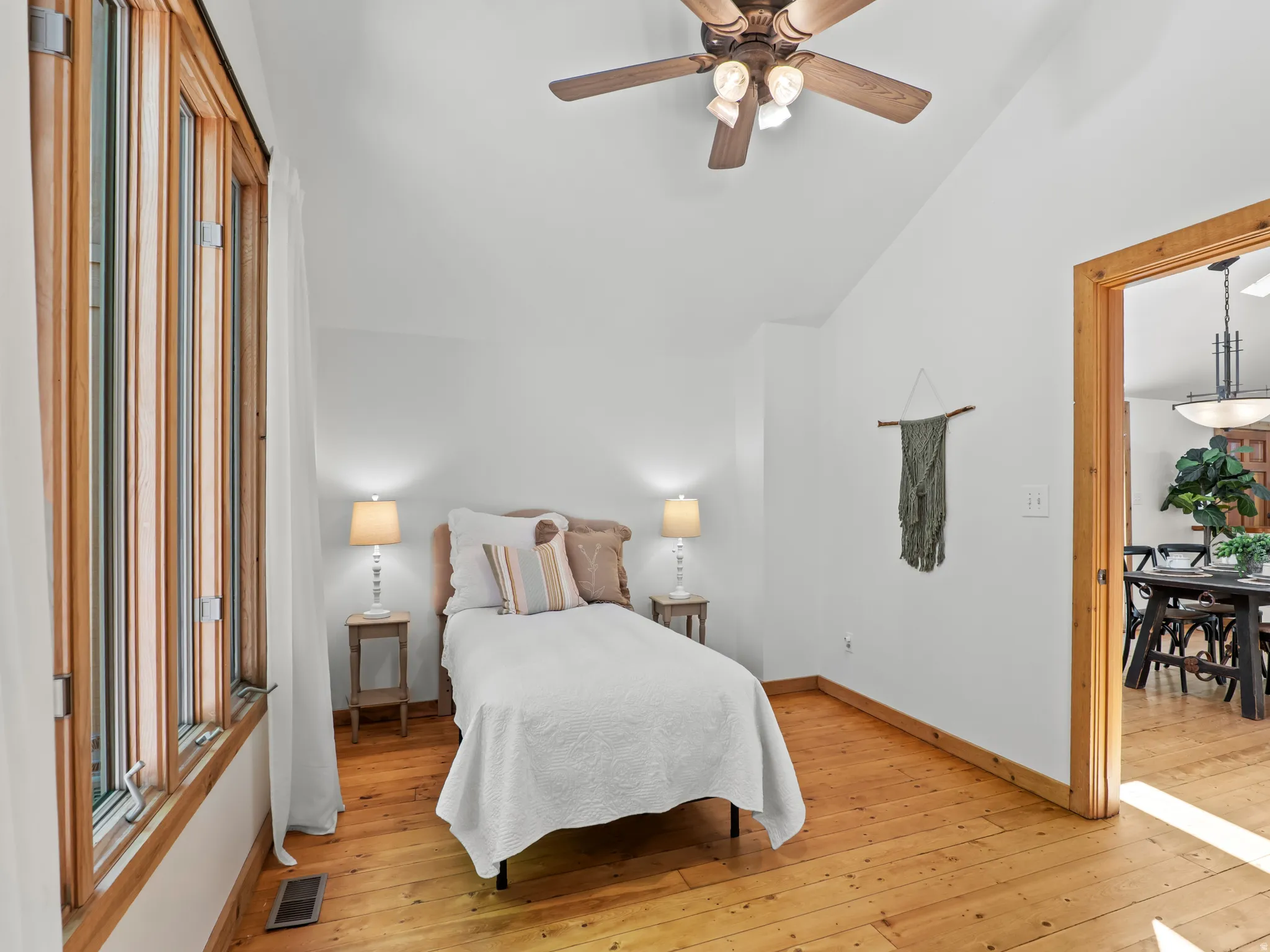 Room featuring natural wood-finish flooring, a vaulted ceiling, and wood-framed windows
