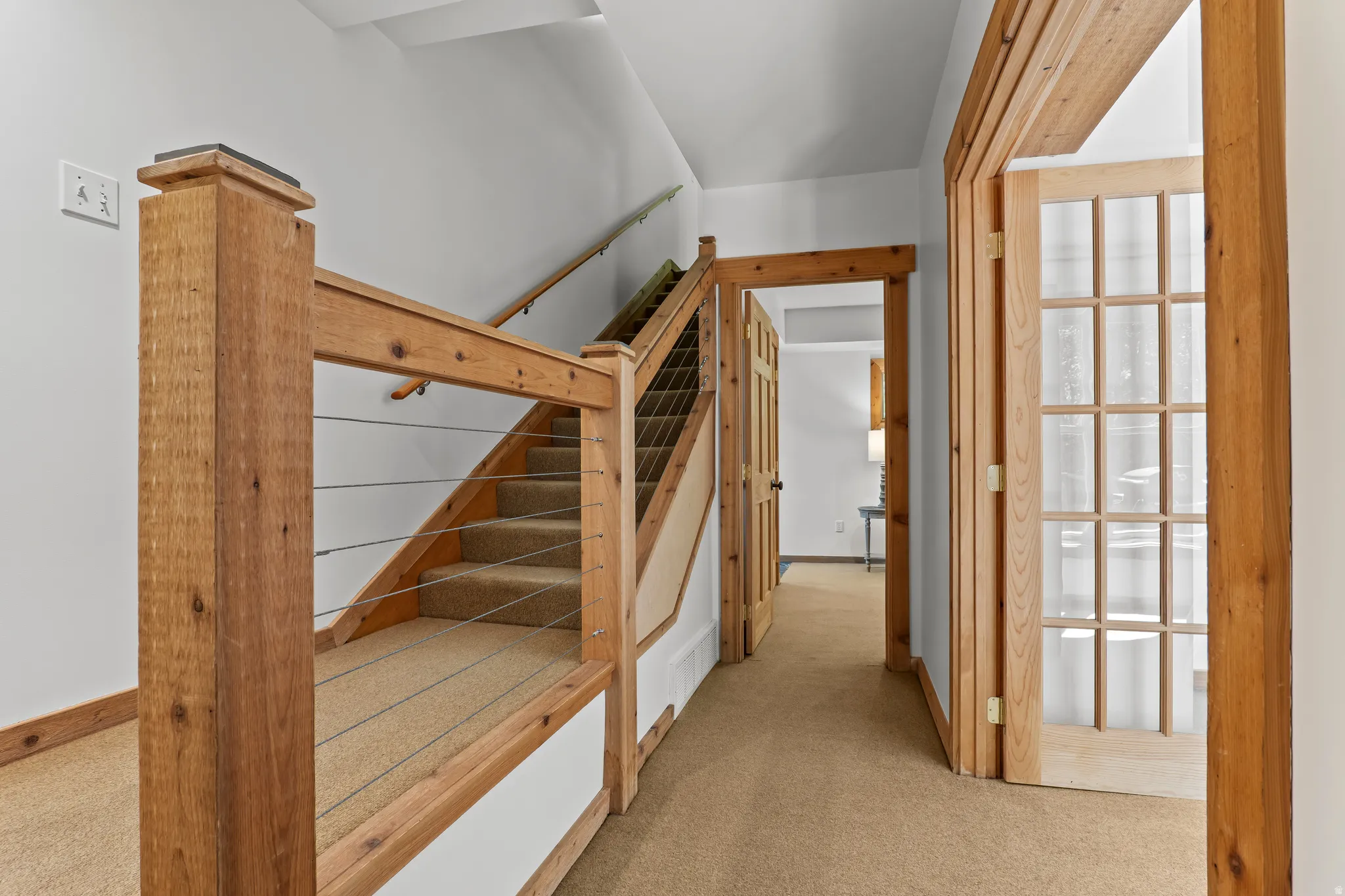 Hardwood and cable railing staircase with carpeted treads