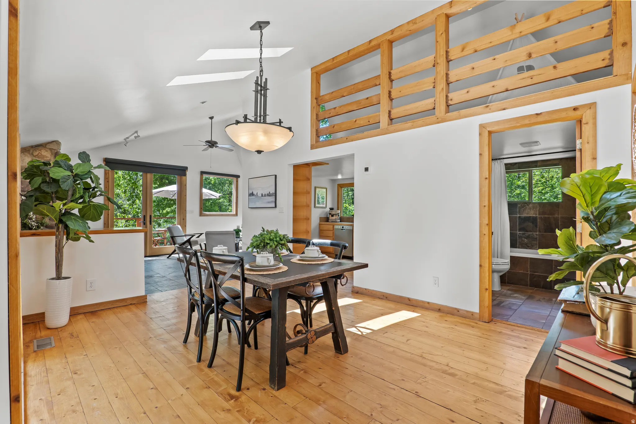 Dining area featuring wood-finish flooring and a vaulted ceiling with skylights and a loft space above the kitchen