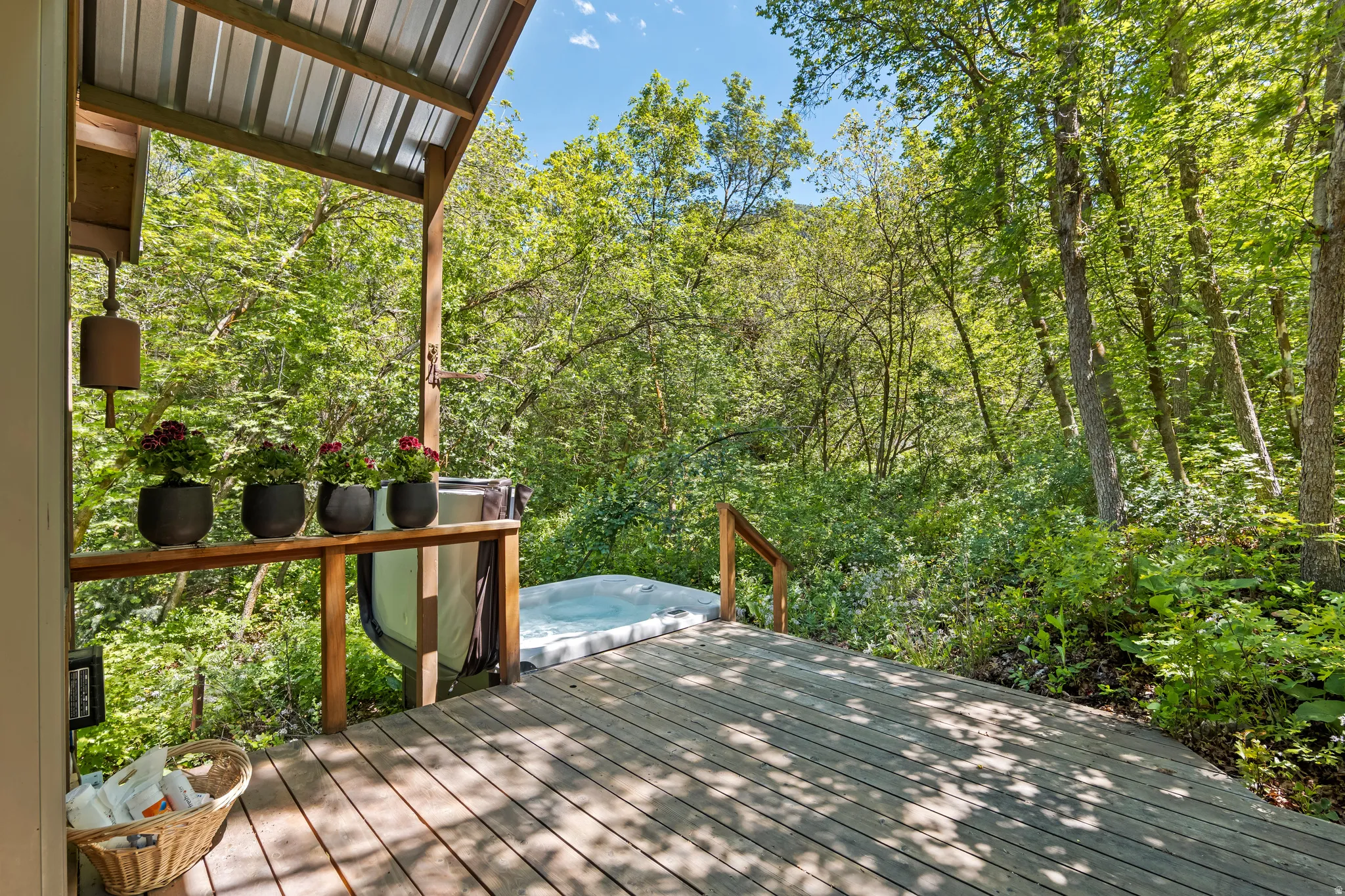 Outdoor covered private deck off the Master Bedroom featuring a  spa surrounded by a capony of trees and nature