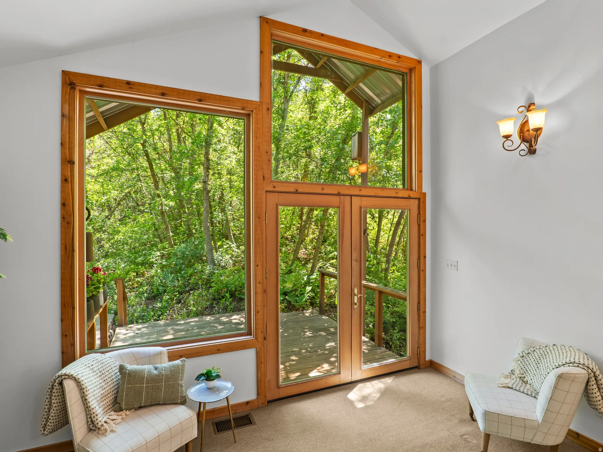 Vaulted ceiling space featuring natural wood window frames and glass panel doors