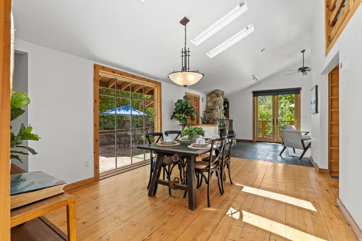 Open dining area with natural wood flooring, a vaulted ceiling and floor to cieling windows
