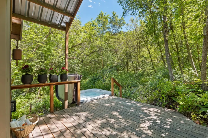 Outdoor covered private deck off the Master Bedroom featuring a  spa surrounded by a capony of trees and nature