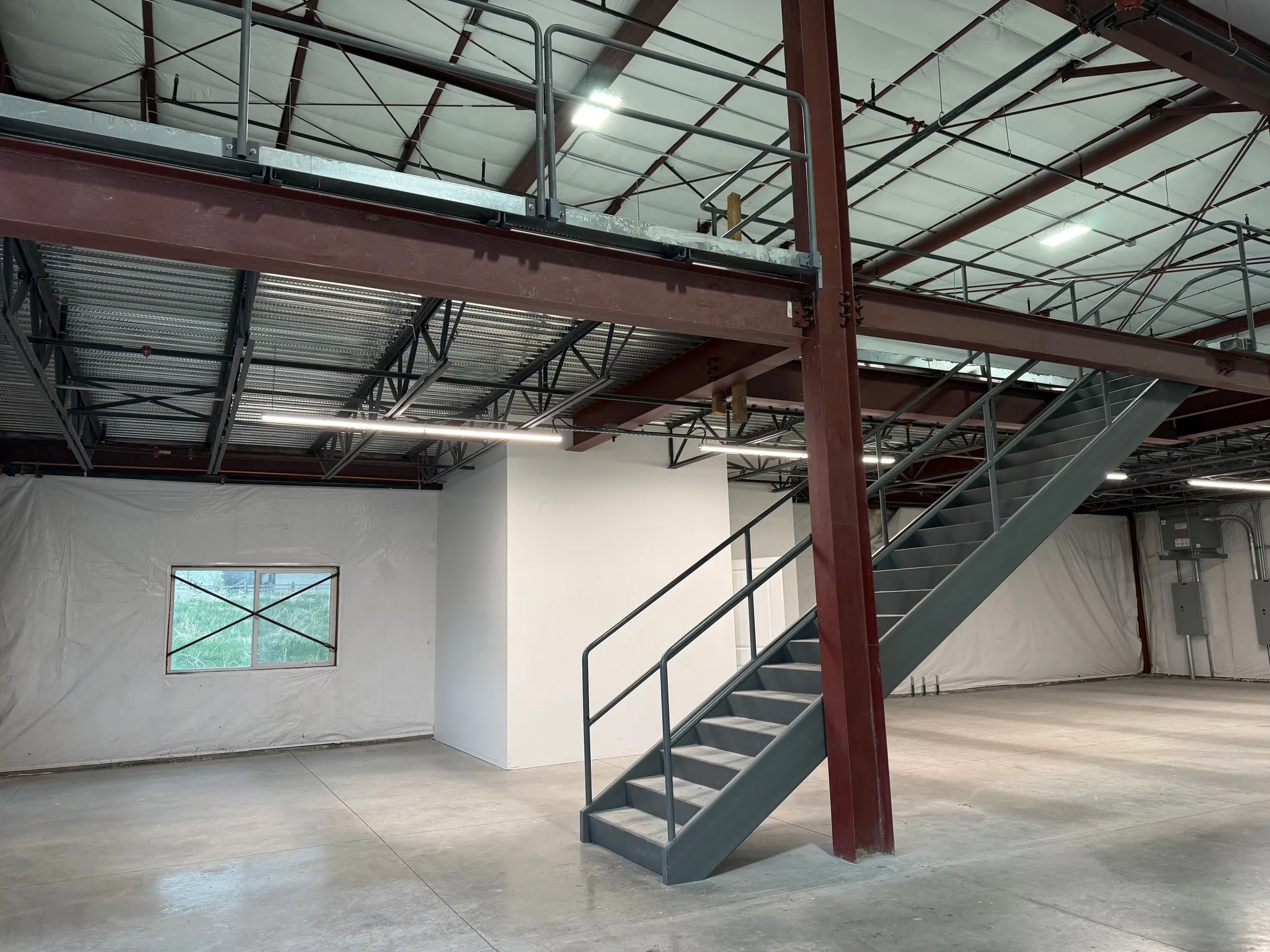 Industrial space featuring a robust steel mezzanine with protective railing and a matching steel staircase