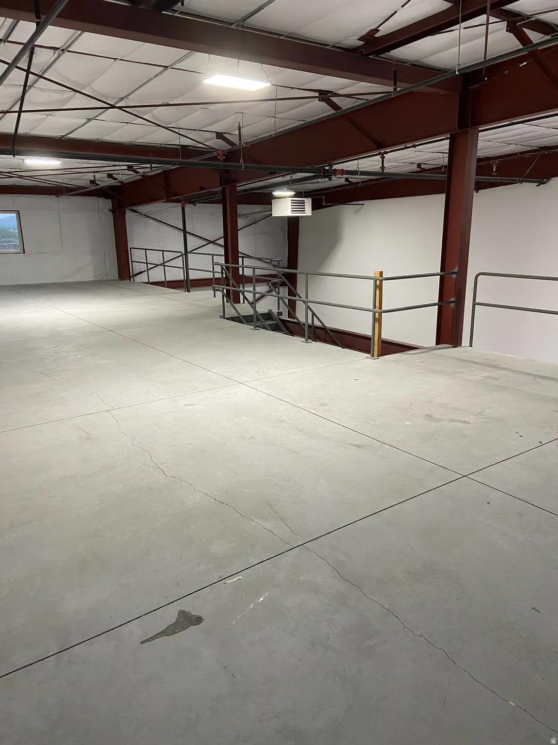 Spacious mezzanine level featuring a concrete floor, industrial-style railings, and exposed structural beams