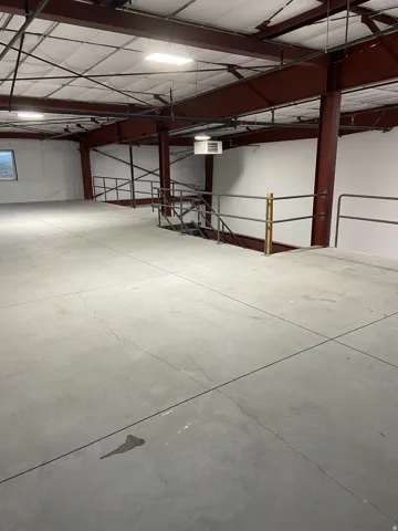 Spacious mezzanine level featuring a concrete floor, industrial-style railings, and exposed structural beams