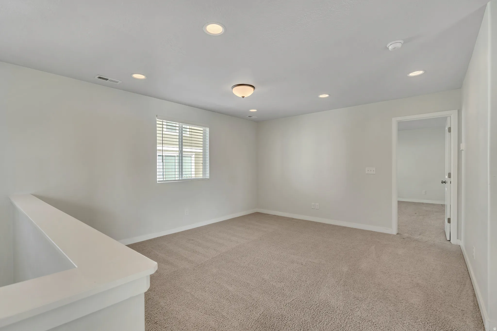 Carpeted room featuring a single window with horizontal blinds, recessed lighting, and a semi-flush mount light fixture
