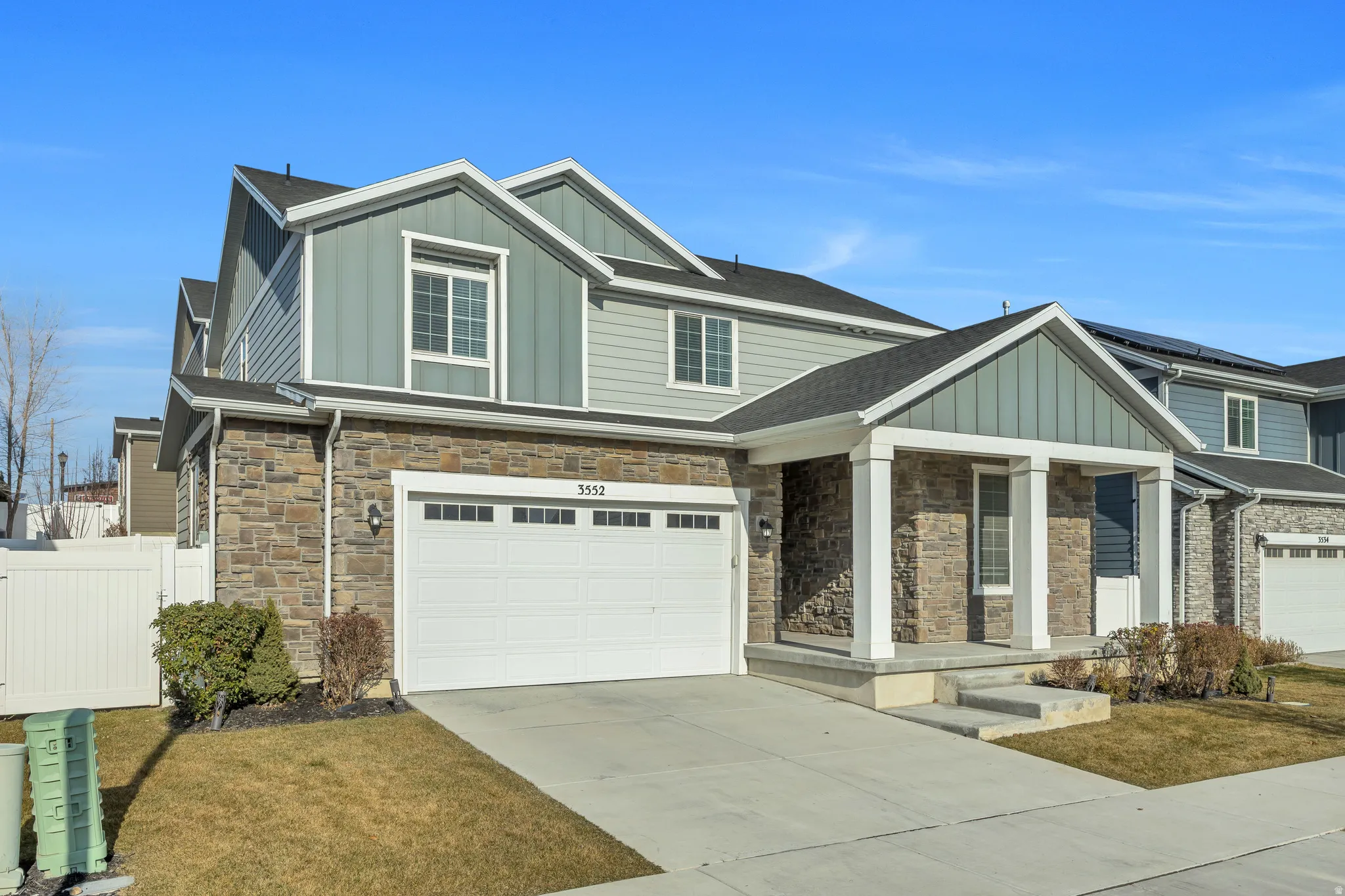 Two-story residence featuring stone and siding exterior with a prominent front porch